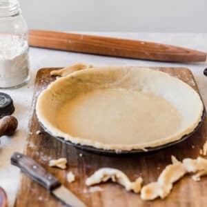 The best pie crust in a metal pan on a wood board with a white background.