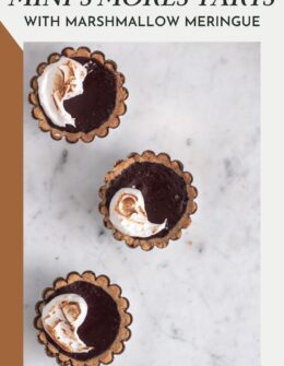A row of three mini s'mores tarts on a white marble counter.