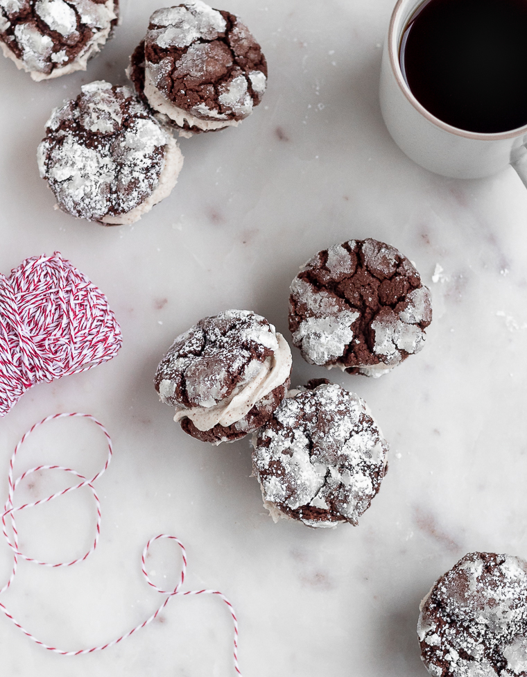An overhead image of six mocha crinkle cookie sandwiches on a marble counter next to a cup of coffee and red and white striped twine.