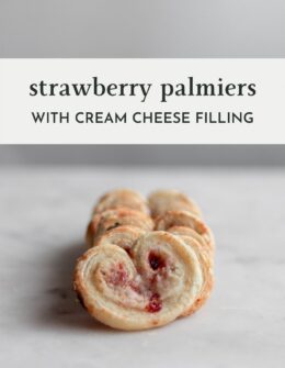 A closeup side image of a row of strawberry palmiers stacked on each other on a white marble table.