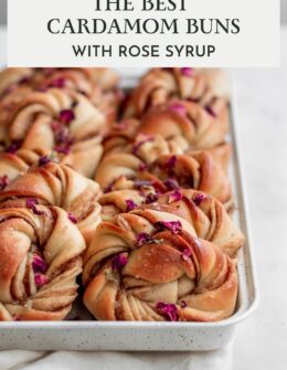 A very closeup side image of rows of rose cardamom buns on a white tray with a white marble background.
