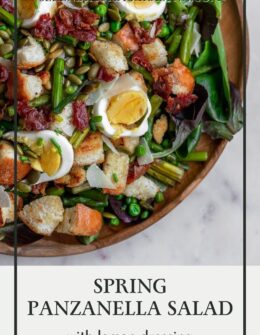 A closeup overhead image of a spring panzanella salad with eggs, croutons, and prosciutto on a wood plate with a white background.