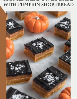 A side image of rows of homemade pumpkin millionaire's shortbread bars on a marble counter with mini orange pumpkins in the background.