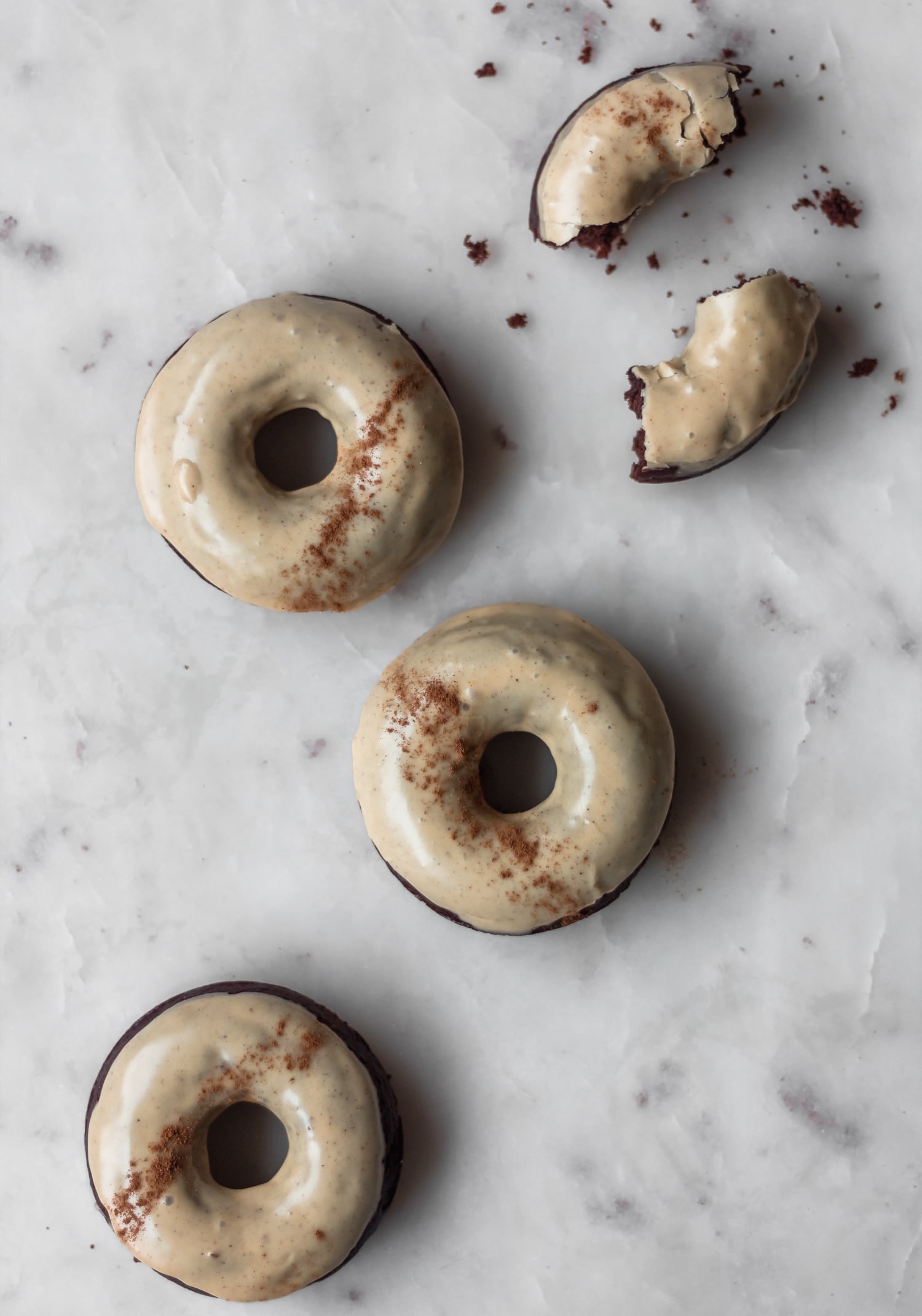 Four chai donuts on a marble counter - the one in the upper right corner is split in half.