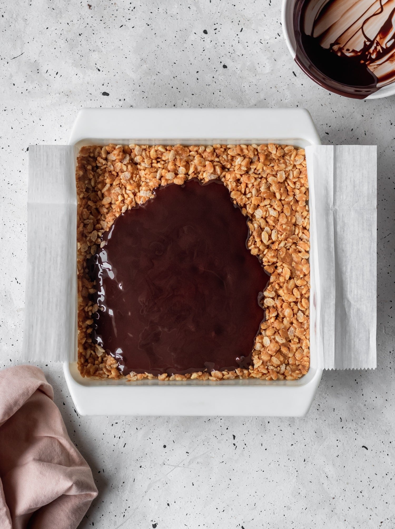 Nutty, Rice Krispie Cereal Treat with Chocolate Drizzled over the top on a grey background.