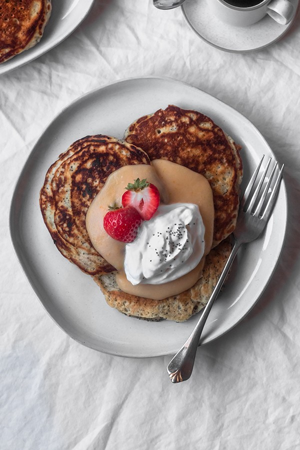 Fluffy poppy seed pancakes with homemade blood orange curd, whipped cream, and fresh berries.