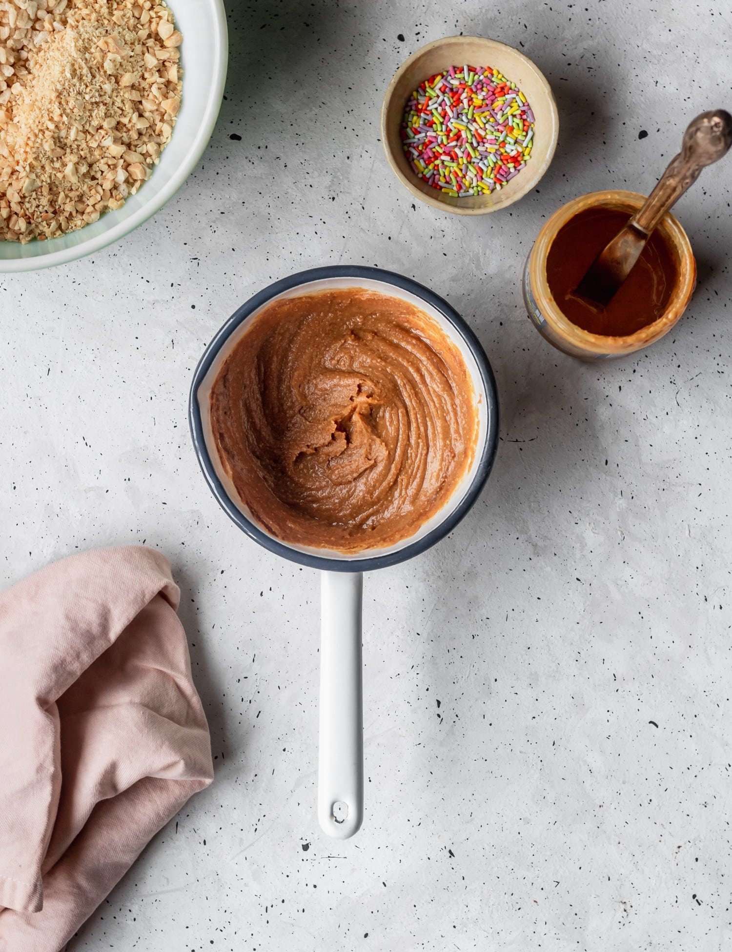 Peanut butter-maple syrup mixture in a pan on a grey, speckled background.