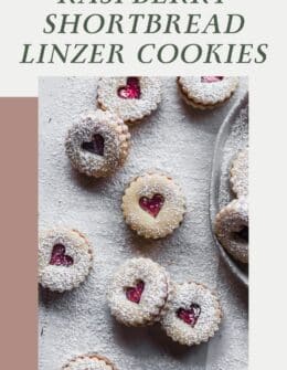 Rows of heart-shaped shortbread linzer cookies on a white counter.
