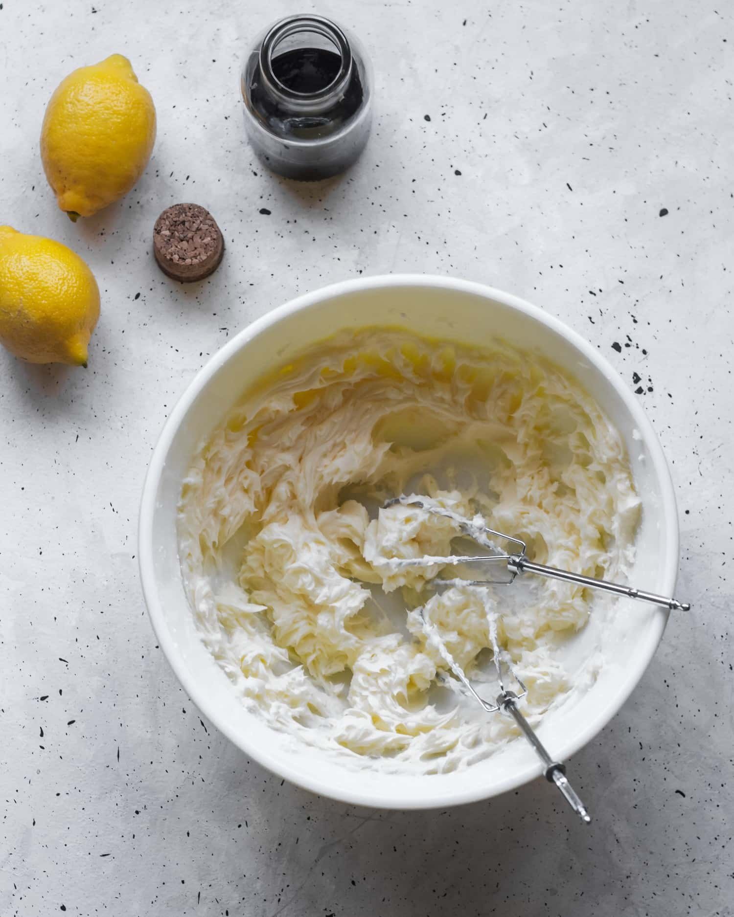 A white bowl filled with butter and sugar sitting on a speckled table.