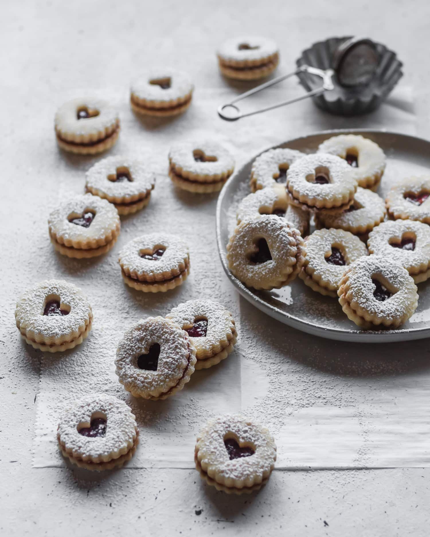 A side shot of a plate of shortbread, covered in powdered sugar, placed on a grey background.