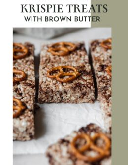 A closeup side image of brown butter Rice Krispie treats with pretzels and chocolate on parchment paper.