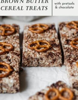 Rows of brown butter rice krispie treats with pretzels and chocolate on a white counter.