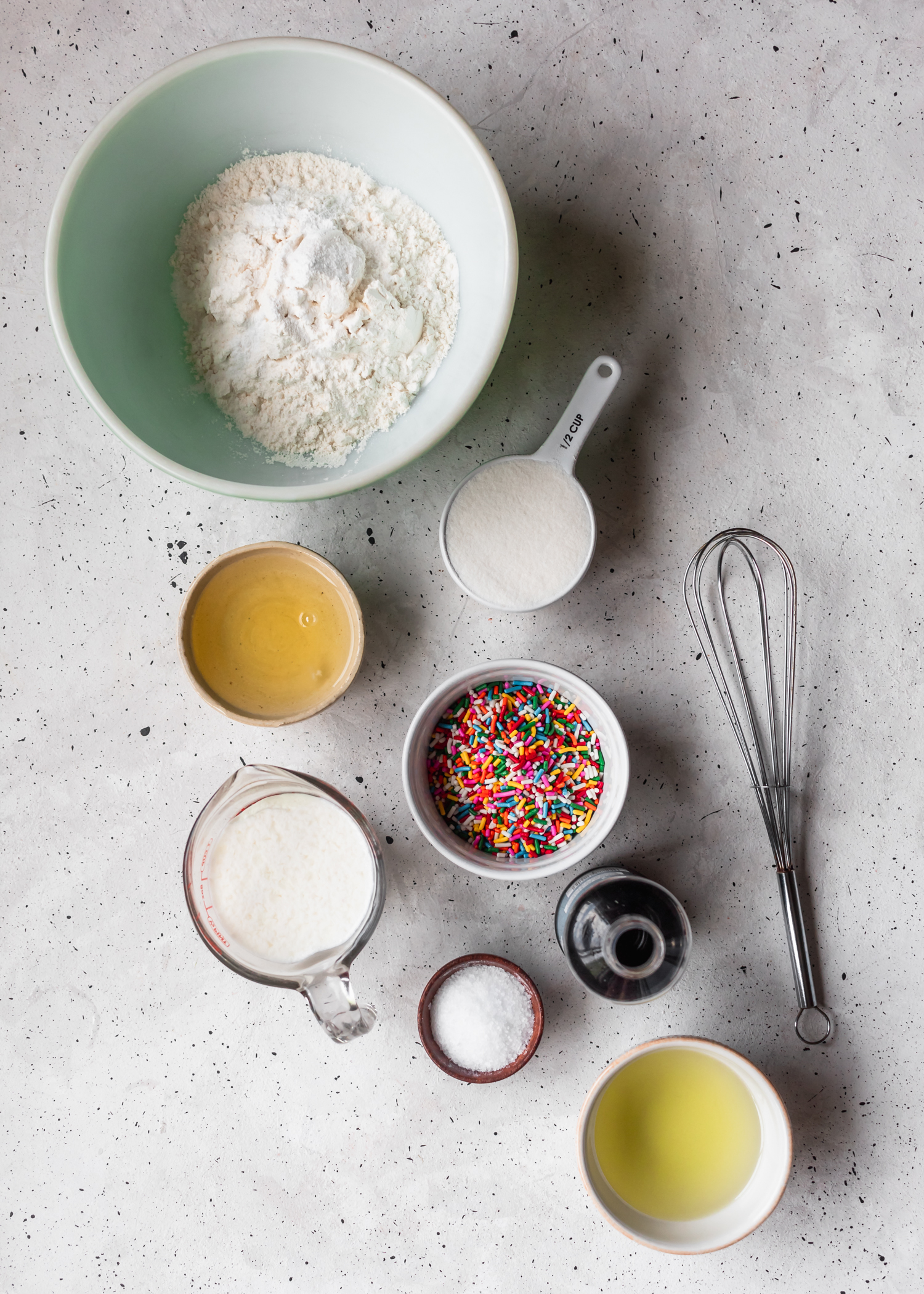 An overhead photo of cake ingredients on a white and grey table.