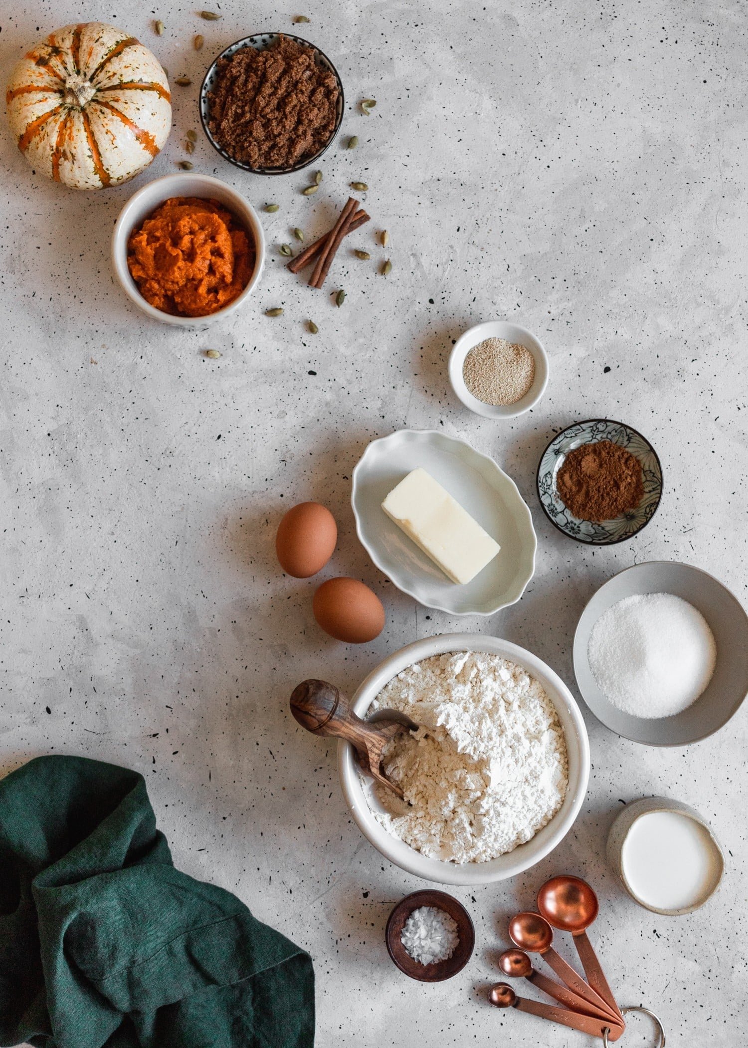 An overhead photo of ingredients for pumpkin cinnamon rolls on a grey table.