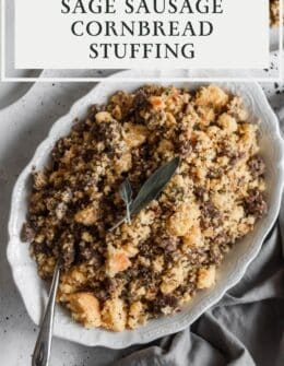 Cornbread stuffing with sausage and sage on a white plate with a grey background.
