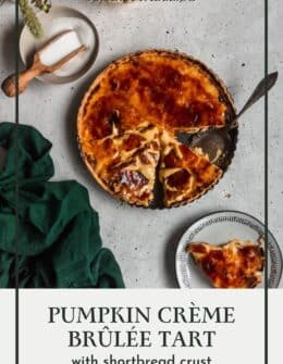 A pumpkin creme brluee tart on a grey counter next to pumpkins and a green linen.