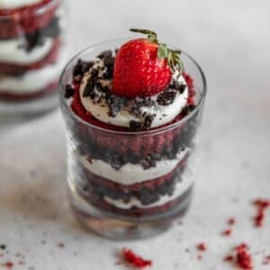 A closeup side photo of a cheesecake red velvet trifle on a grey counter.