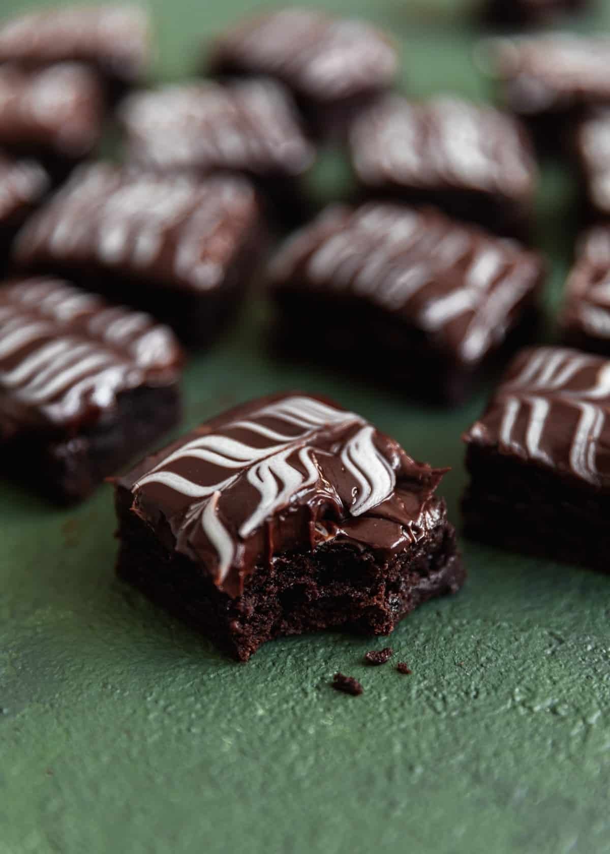 An Irish coffee brownie with a bite taken out of it on a dark green background surrounded by more brownies.