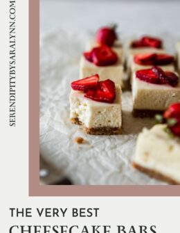 A closeup side image of rows of strawberrry cheesecake bars on white parchment paper. The front bar has a bite taken out of it.