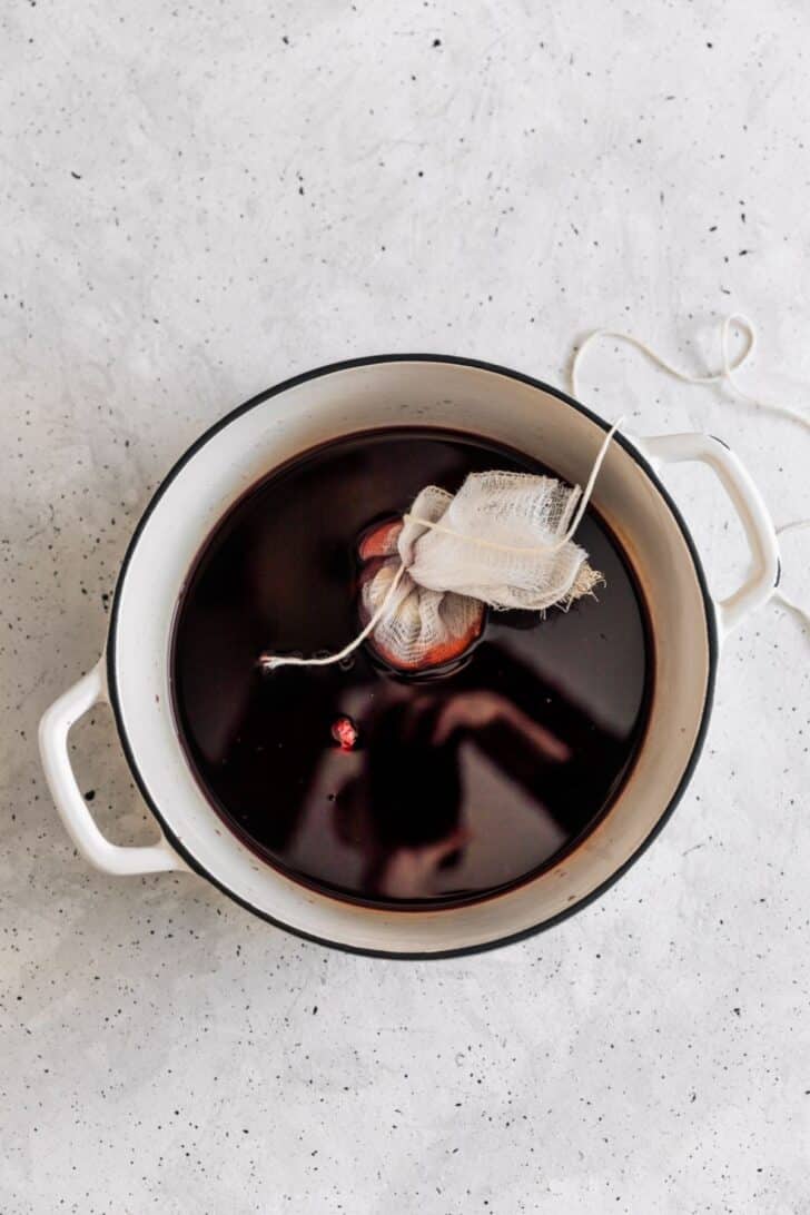 A pot of red wine with a satchel of spices in the center.