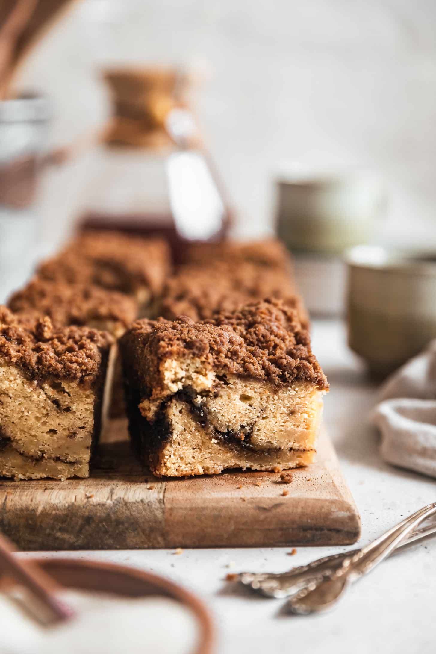 Ideas for a Cocktail Party | Brown butter banana coffee cake on a wood board next to coffee cups, a Chemex, and vintage forks with a white background.