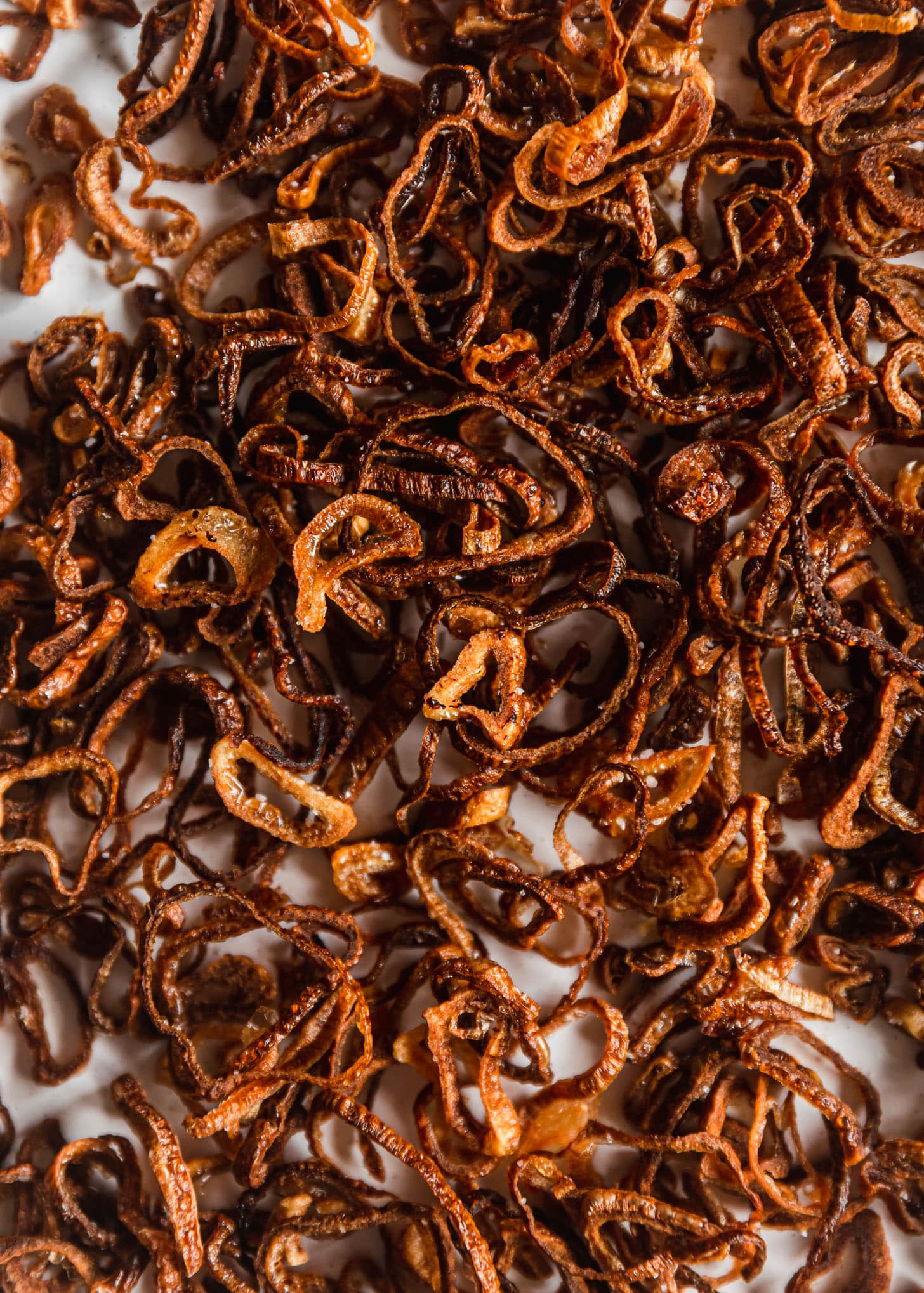 Crispy fried shallots on a white plate.