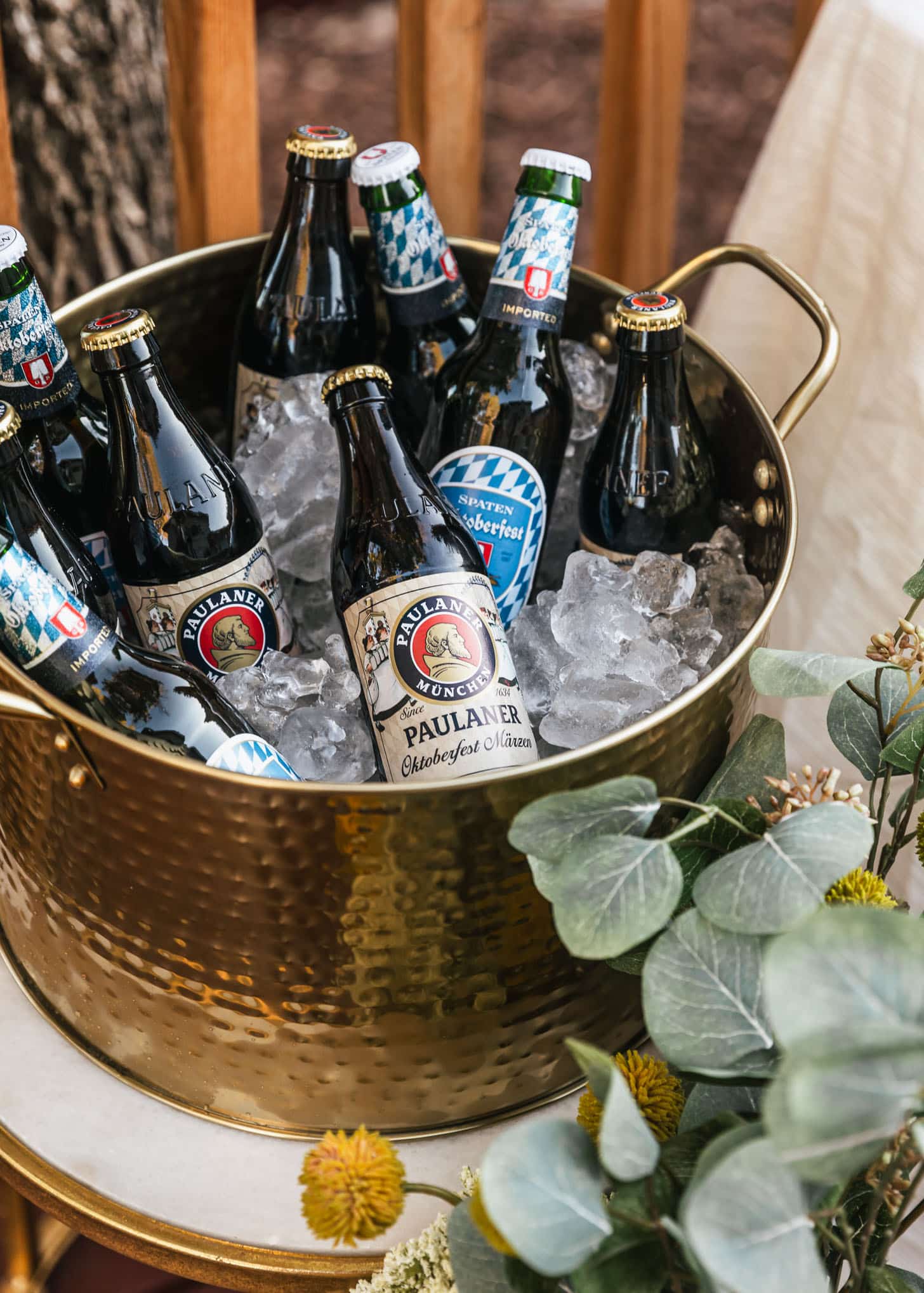 A gold cooler with beer next to eucalyptus leaves.