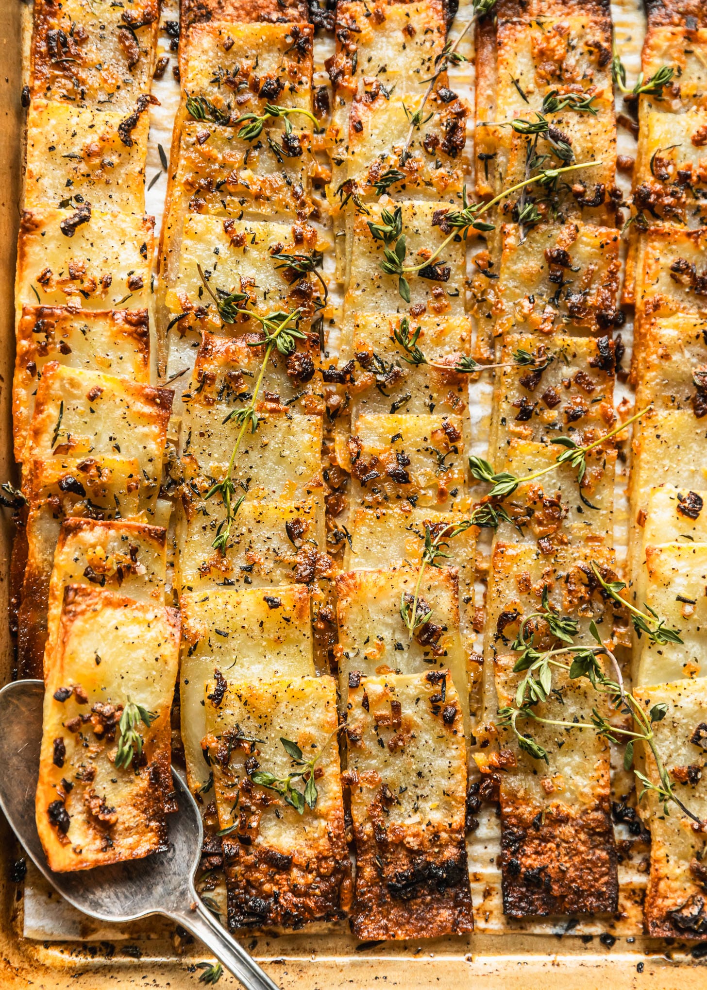 Domino potatoes with shallots, rosemary, and fresh time on a gold sheet pan.