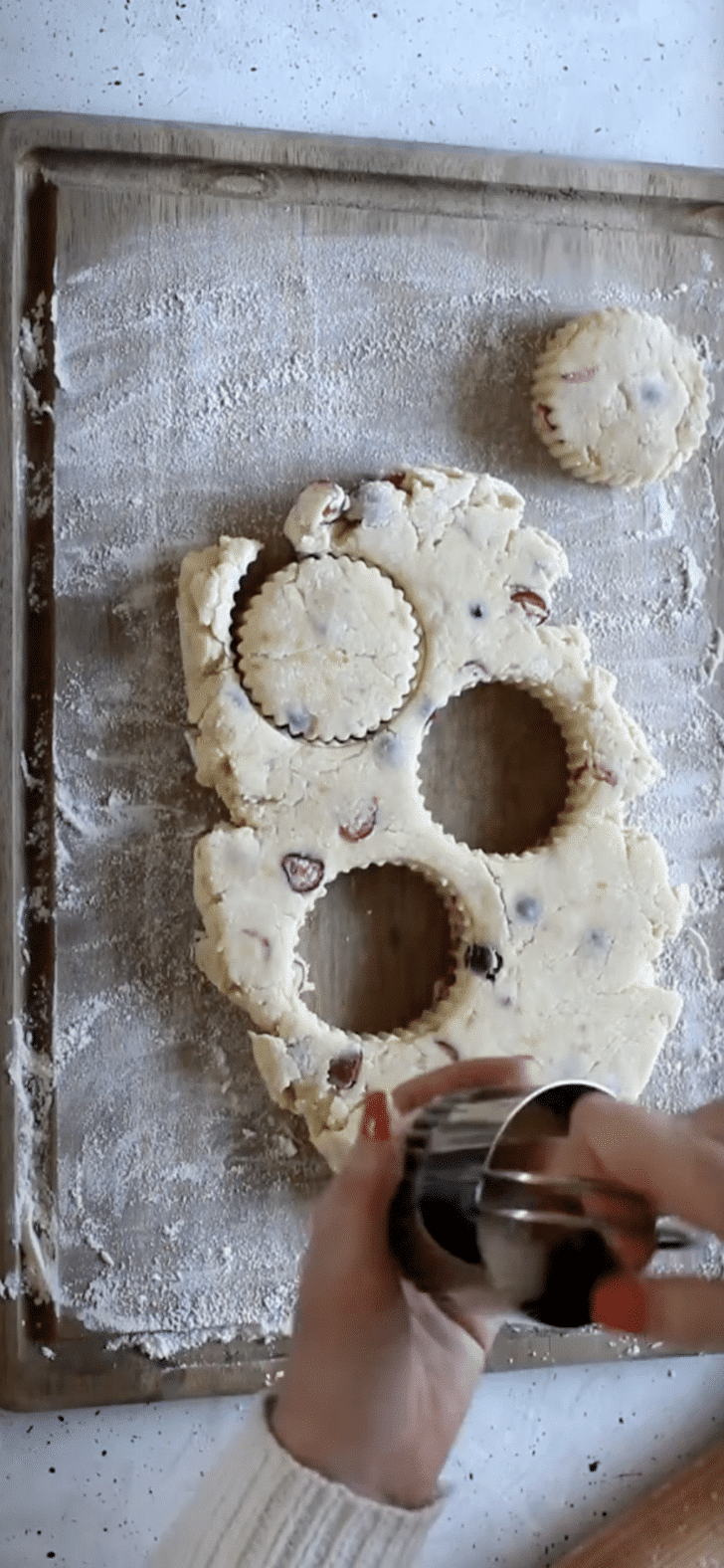 Hands using a cookie cutter to cut out scones.
