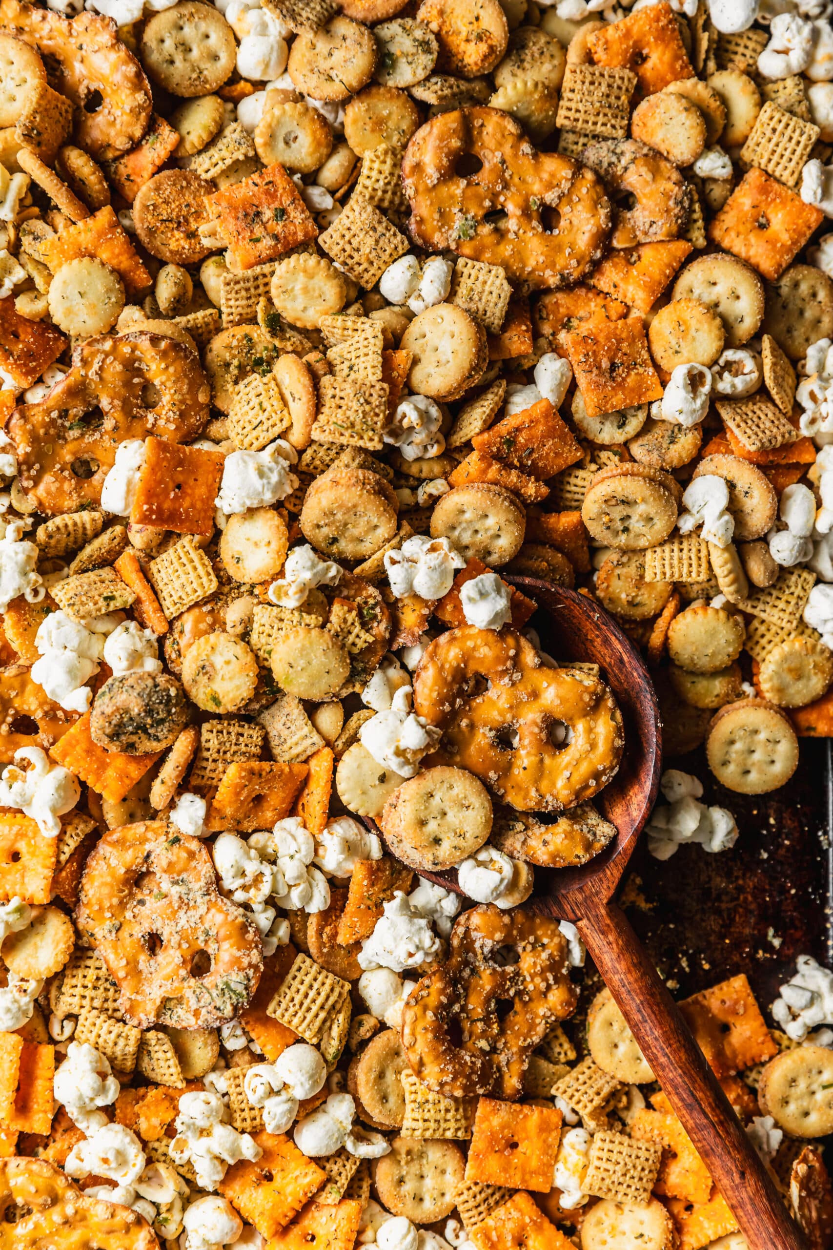 A wood spoon scooping spicy ranch Chex mix.