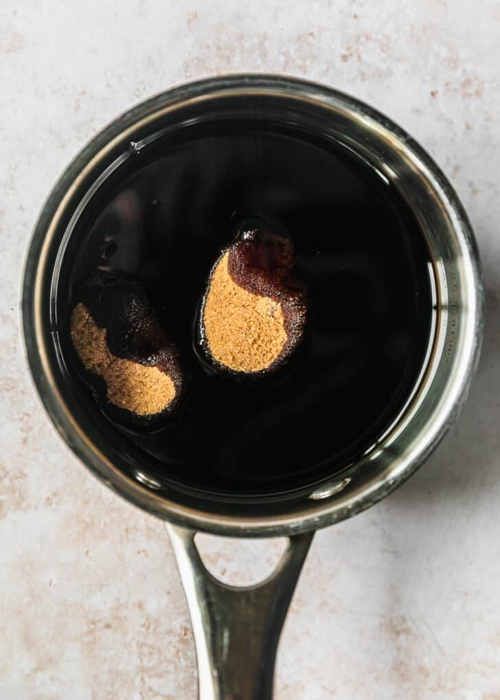 A saucepan with balsamic and brown sugar on a tan counter.