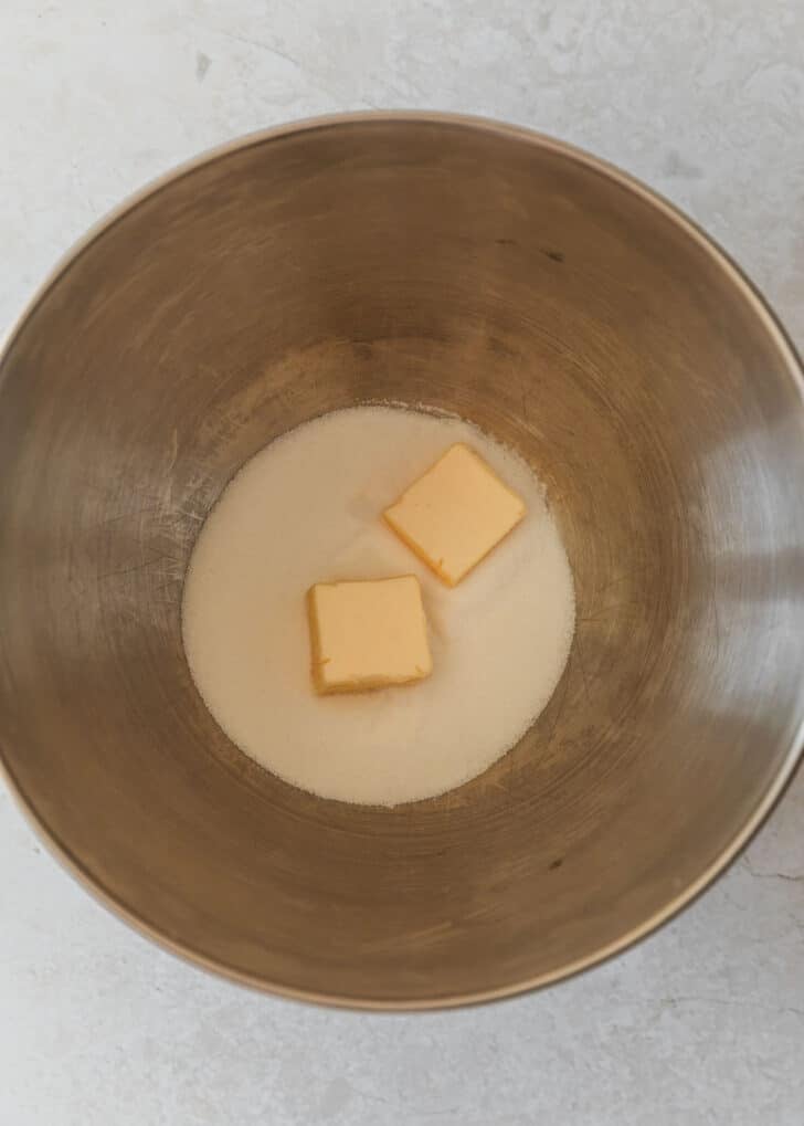 A silver bowl of sugar and butter on a marble counter.