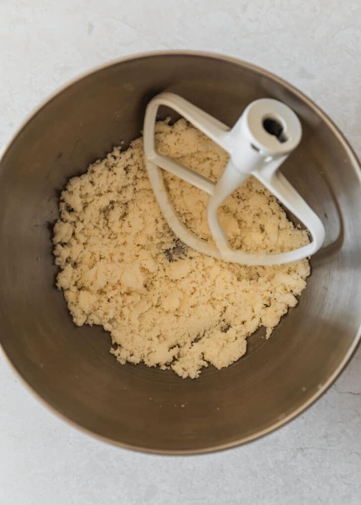 A silver bowl of creamed butter and sugar on a white counter.