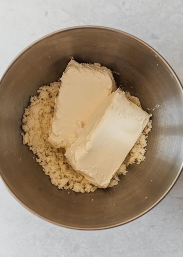 A silver bowl with creamed butter and sugar and cream cheese.