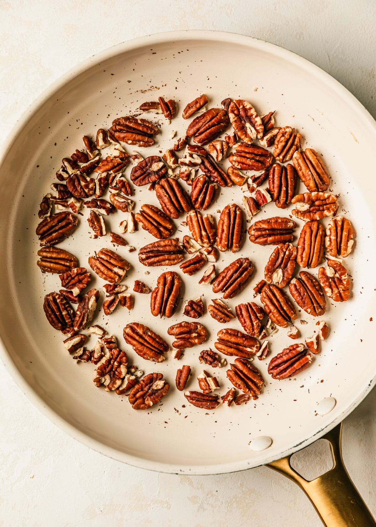 A white pan of toasted pecans on a white counter.