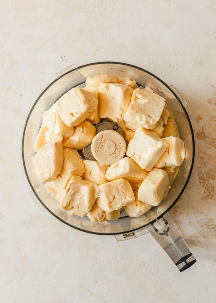 A food processor with brie on a white counter.