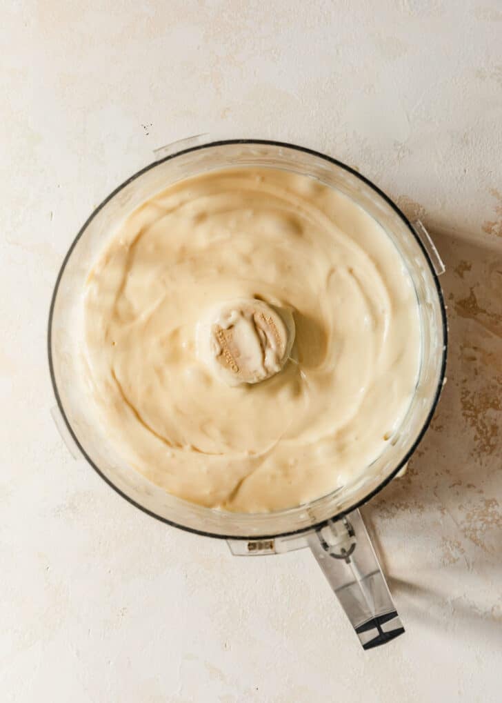 A food processor of whipped brie cheese on a white counter.