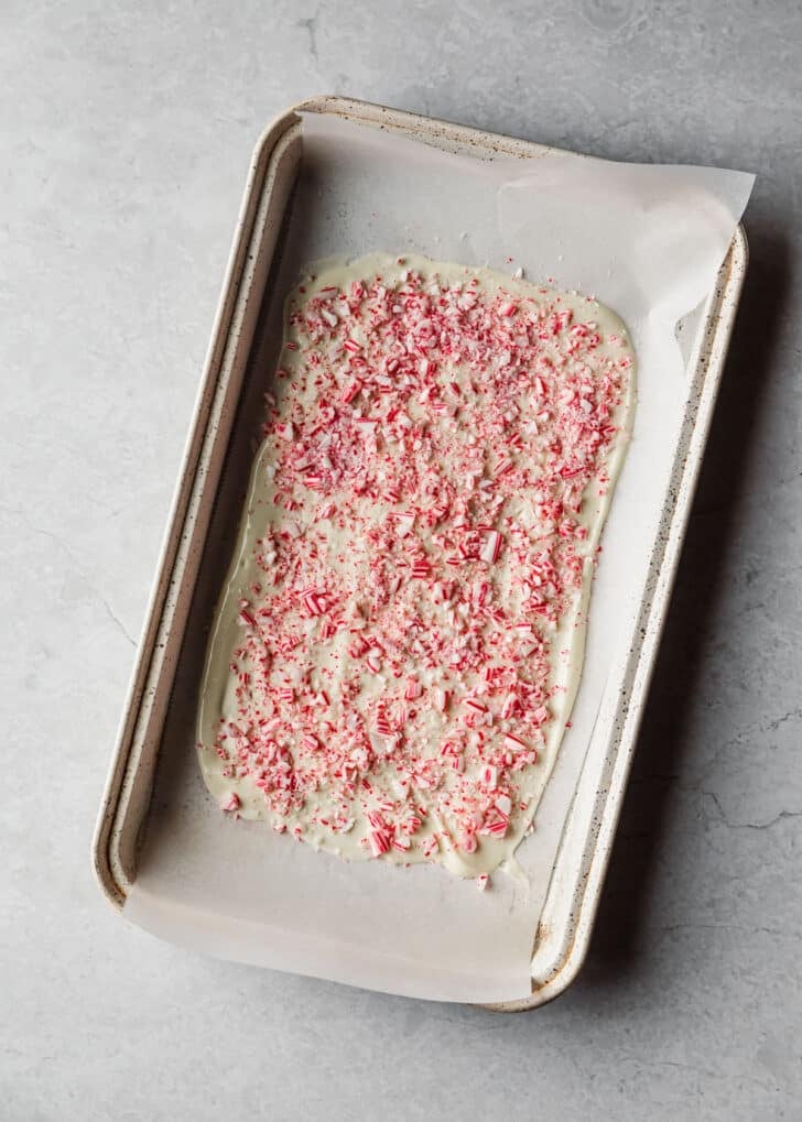 A white sheet pan with peppermint bark on a marble counter.