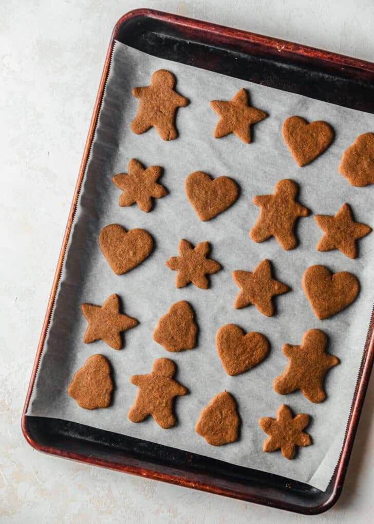 Baked mini gingerbread cookies on a sheet pan.