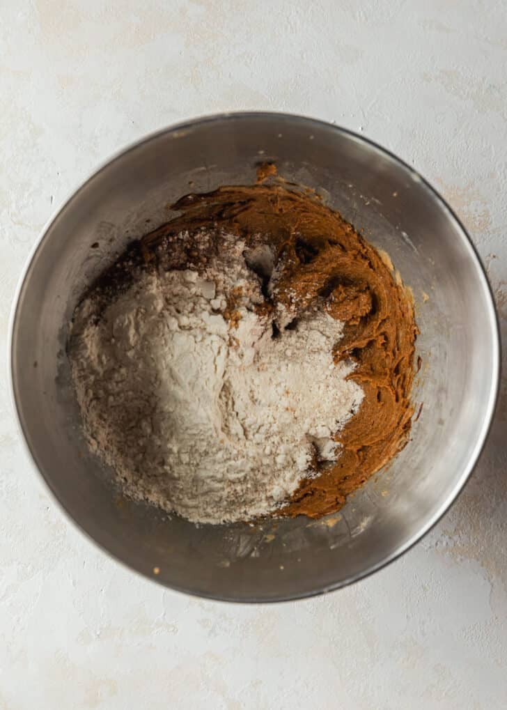 A silver bowl of butter, brown sugar, molasses, and flour on a tan counter.