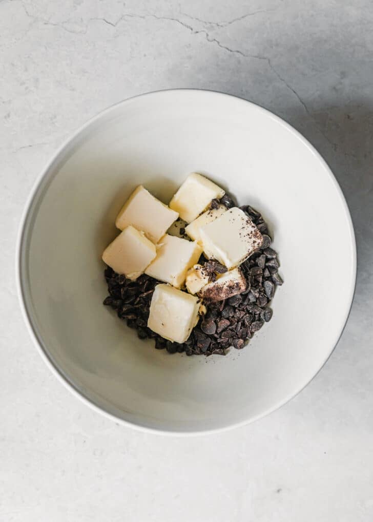 A white bowl of butter and chocolate on a white counter.