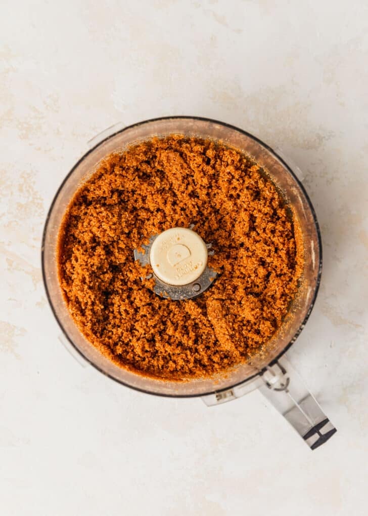 A food processor of graham cracker crust on a tan counter.