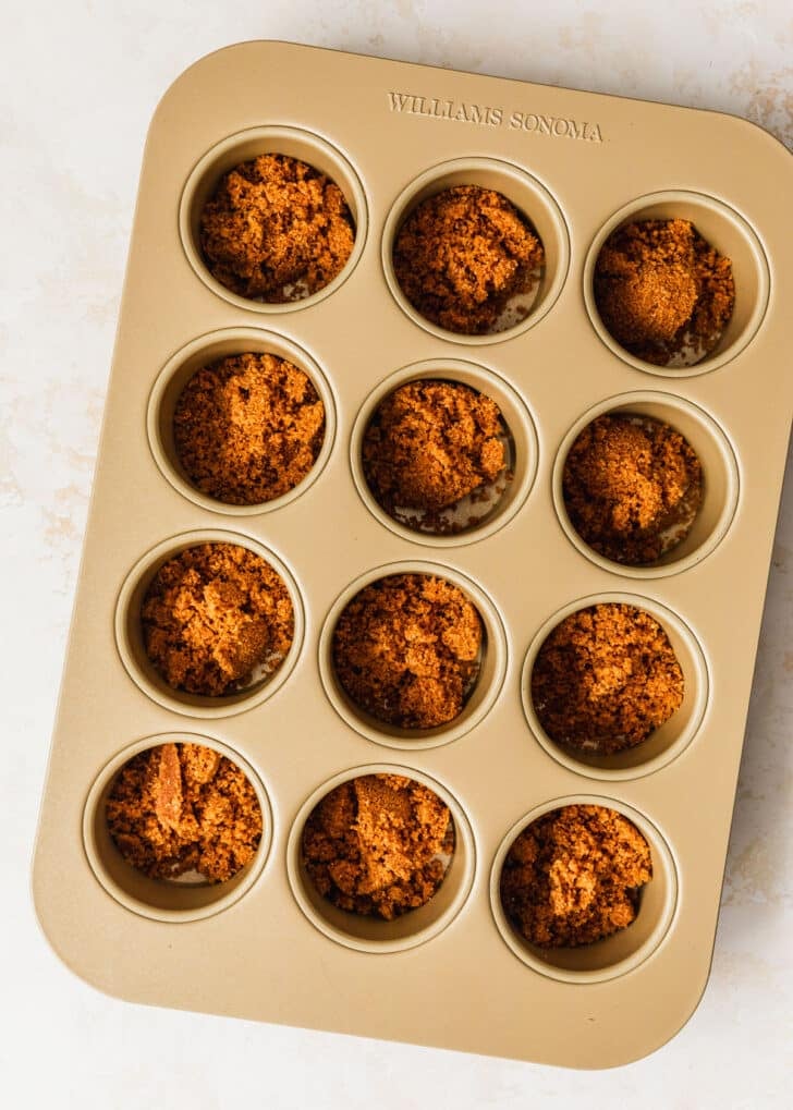 A mini cheesecake pan with graham cracker crust on a beige counter.