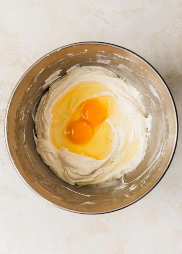 A silver bowl of cream cheese filling and eggs on a beige counter.