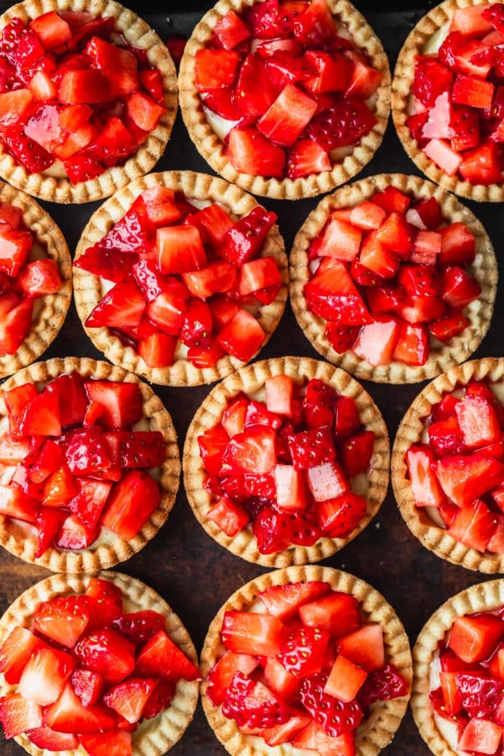A pan of rows of strawberry custard tartlets.