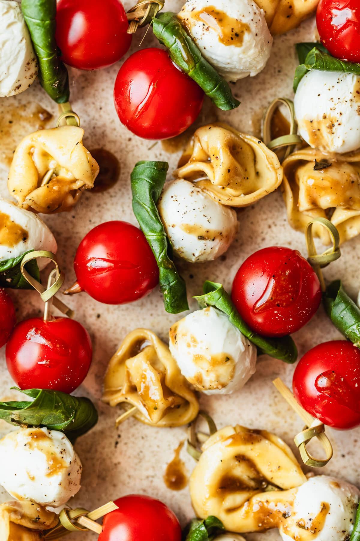 Rows of tortellini Caprese skewers on a tan platter.