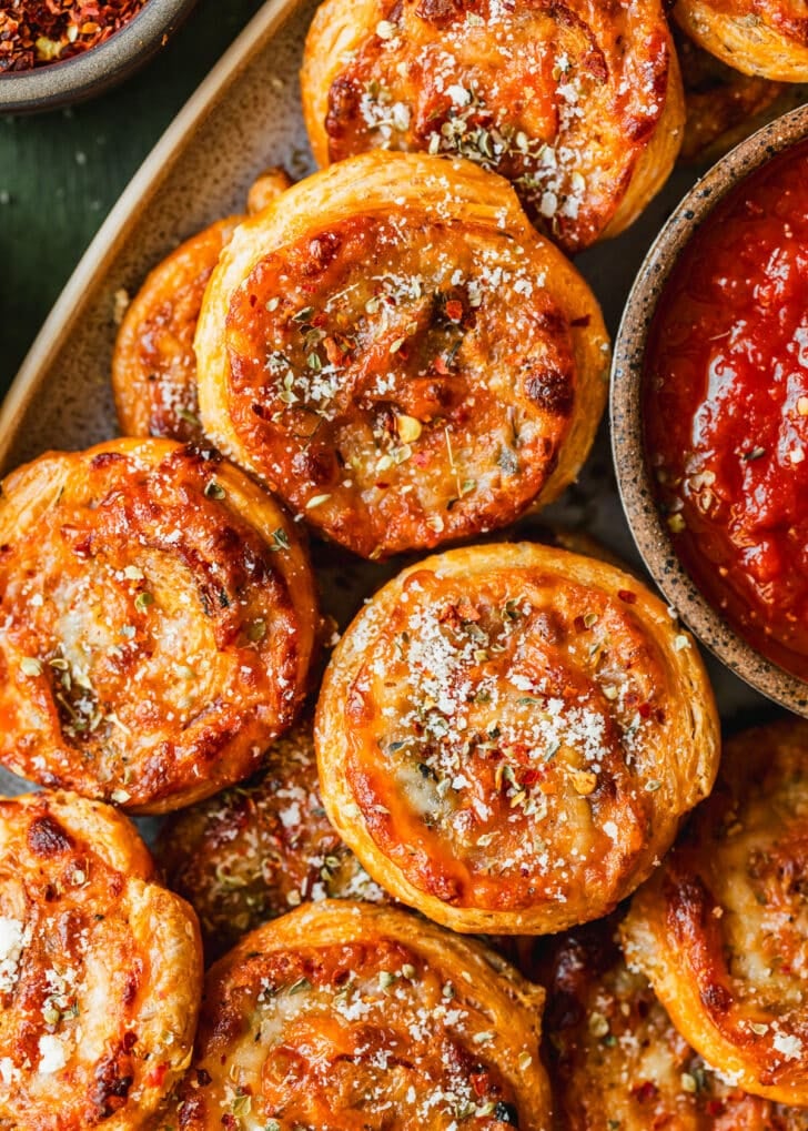 A stoneware platter of pizza scrolls on a green counter.