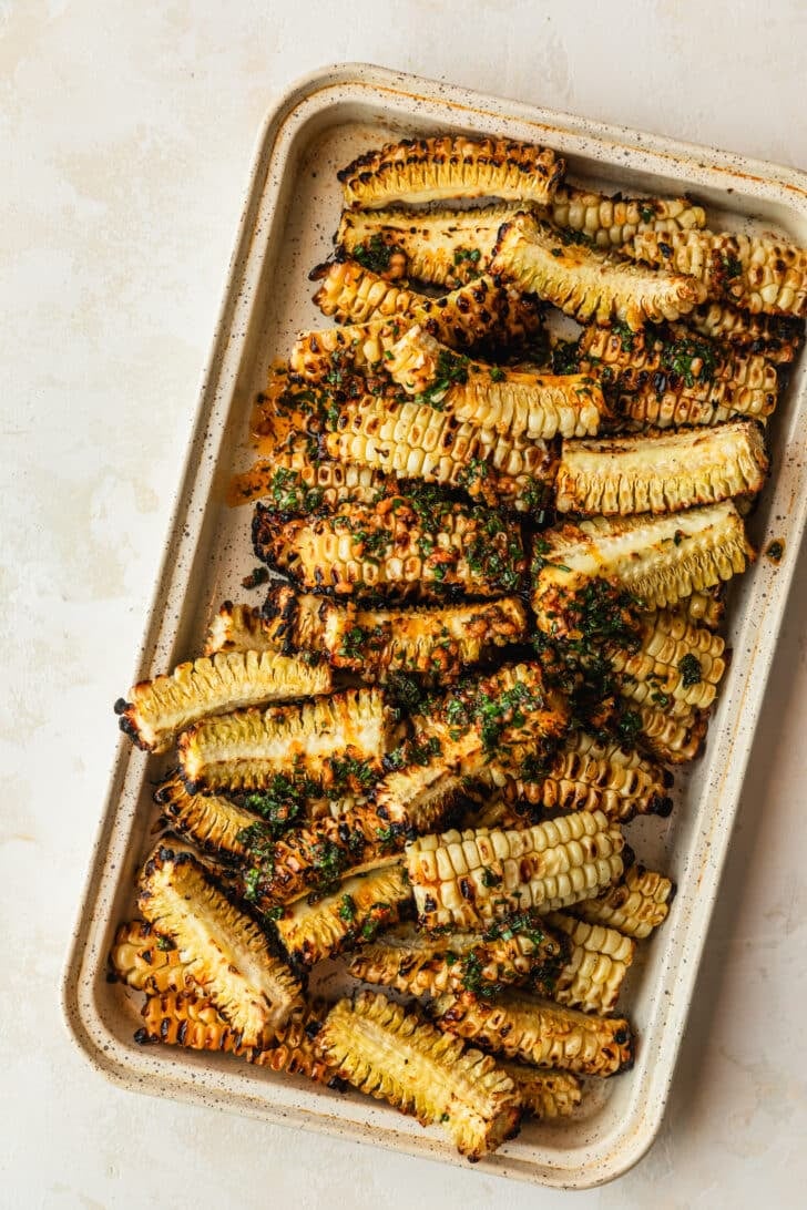 A white pan of grilled veggies with herb butter.