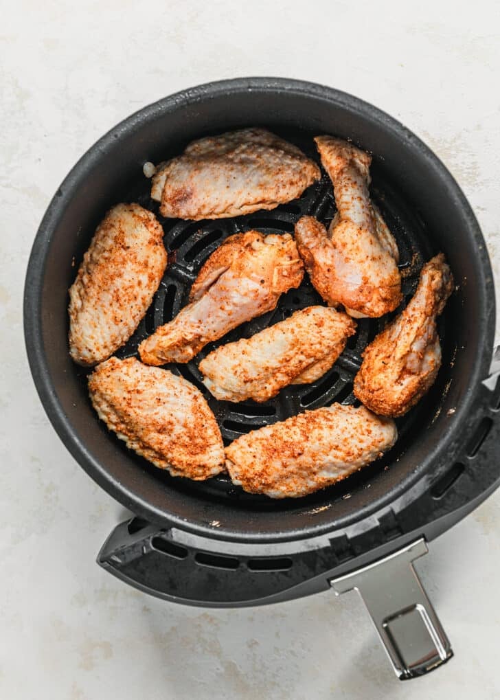 Wings in an air fryer on a white counter.