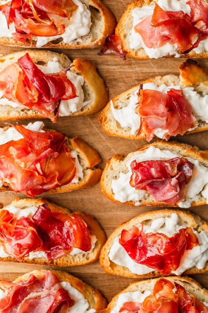 Rows of crostini topped with burrata and prosciutto.